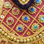 Gastronomic Gems - A close up of a gold and red dress with gold and red beads