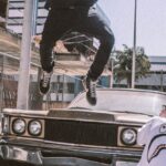 Street Fashion - Man Jumping on Front of Brown Car