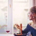 Italian Elegance - Woman Sitting on Chair While Eating Pasta Dish