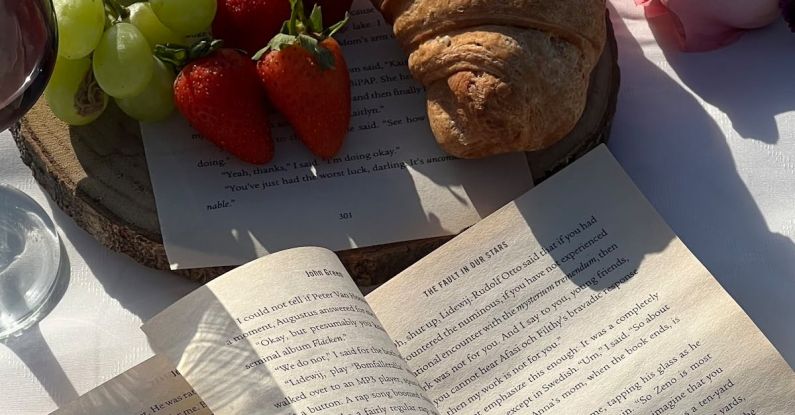 Picnic Spots - A book, bread, grapes and strawberries on a beach